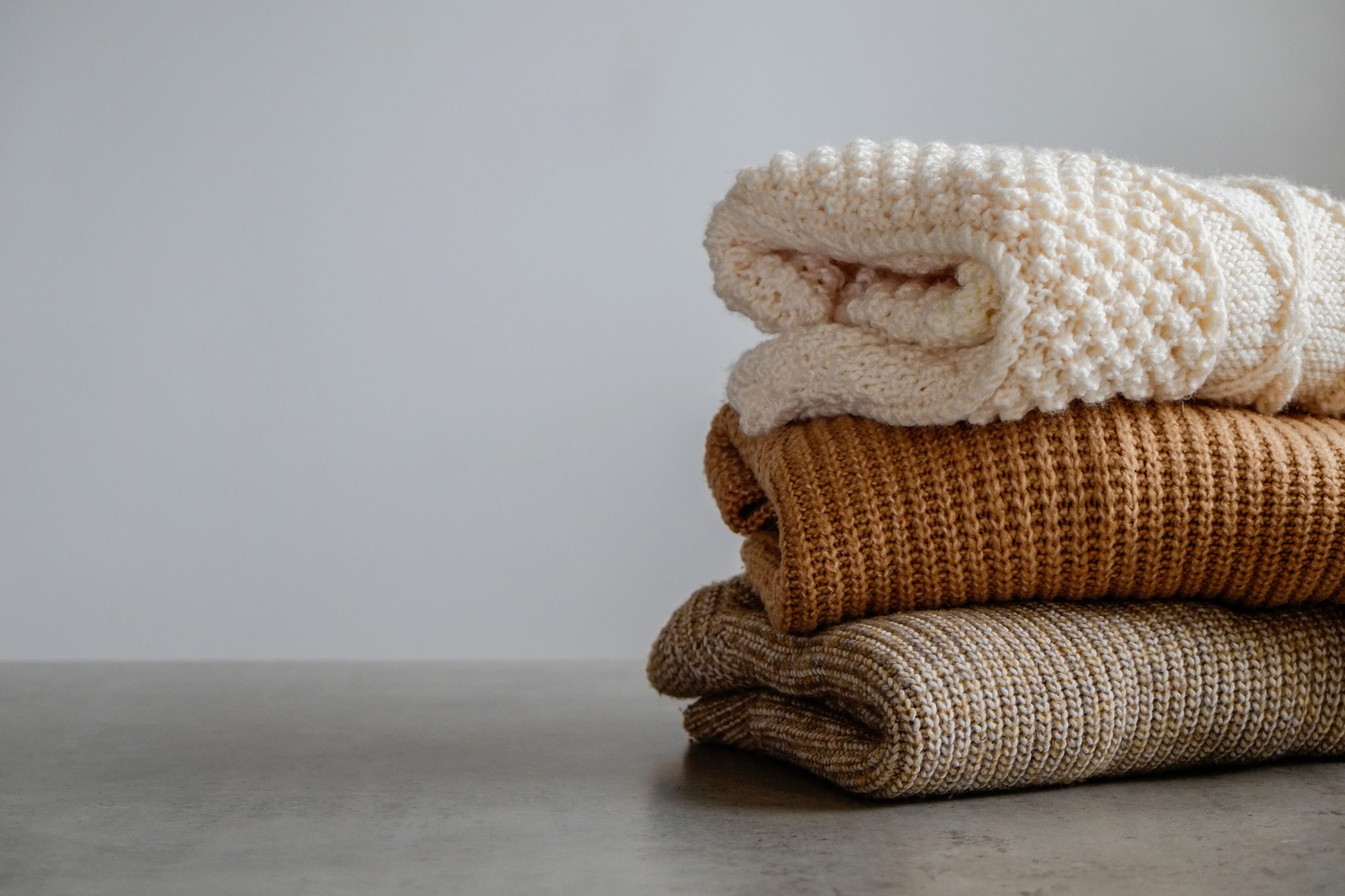 Bunch of knitted warm pastel color sweaters with different knitt
